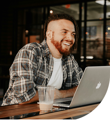 Arbeiter sitzt an einem Tisch, trinkt Kaffe und unterhält sich per Videokonferenz mit Arbeitskollegen