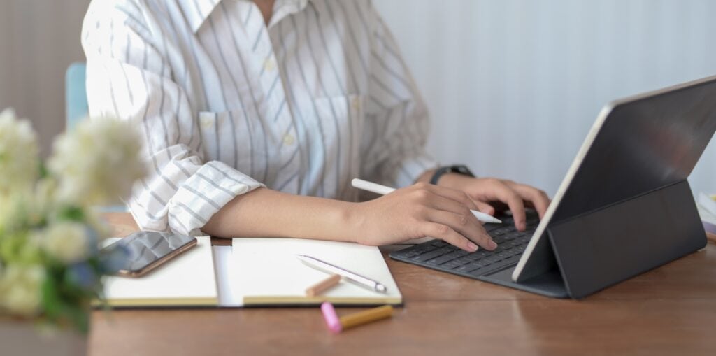 Gefahrgutbeauftragter arbeitet am Laptop und stützt seinen Arm auf ein Notizbuch